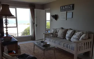 a living room with a couch and a large window at Strandloper Apartments in Hermanus