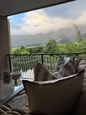 a couch on a balcony with a view of mountains at Franschoek Lermitage Villa 33 Three Bedroom Lake View in Franschhoek