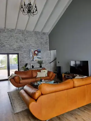 a living room with leather couches and a television at Scenic Mountain & Winelands views, Modern Design in Tygerberg Hills