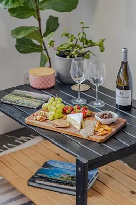 a table with a tray of food and wine glasses at Hermanus Waterfront Boho Studio Apartment, Whale Coast Hideaway in Hermanus