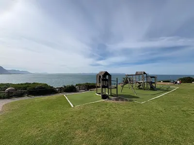 a playground in a field next to the water at Hermanus Waterfront Boho Studio Apartment, Whale Coast Hideaway in Hermanus