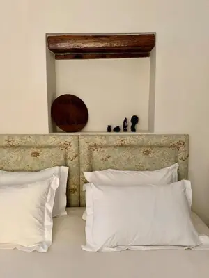 a bed with white pillows and a wooden headboard at Sevilo Farmhouse in Stellenbosch