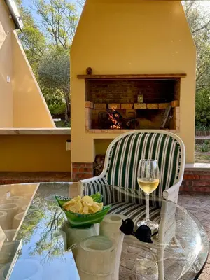 a glass of wine on a glass table in front of a fireplace at Sevilo Farmhouse in Stellenbosch