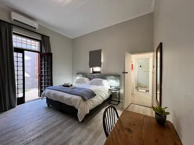 a bedroom with a bed and a table with a chair at Avignon Guesthouse in Worcester