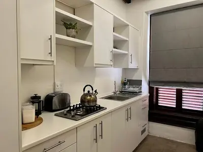 a kitchen with white cabinets and a tea kettle on the stove at Avignon Guesthouse in Worcester