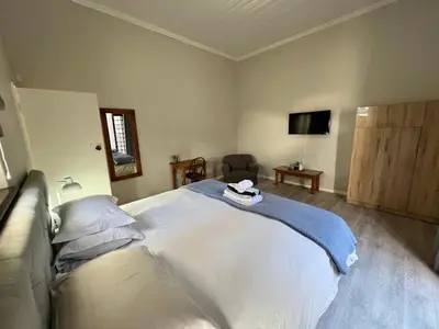 a bedroom with a large white bed and a chair at Avignon Guesthouse in Worcester