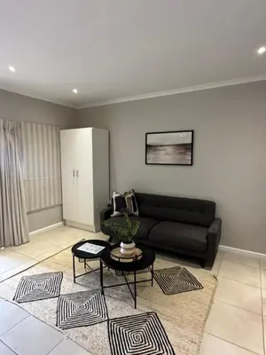 a living room with a black couch and a table at Best Rest Somerset 3 in Somerset West