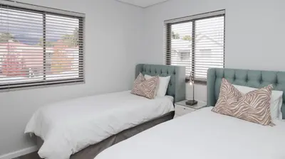 a bedroom with two beds and two windows at Happy Days in Paarl