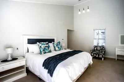 a bedroom with a large white bed with blue pillows at The Joyful Tortoise in Hermanus