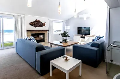 a living room with two blue couches and a fireplace at The Joyful Tortoise in Hermanus