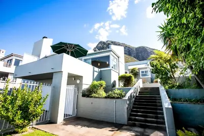 a white house with mountains in the background at The Joyful Tortoise in Hermanus