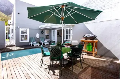 a patio with a table and chairs and an umbrella at The Joyful Tortoise in Hermanus