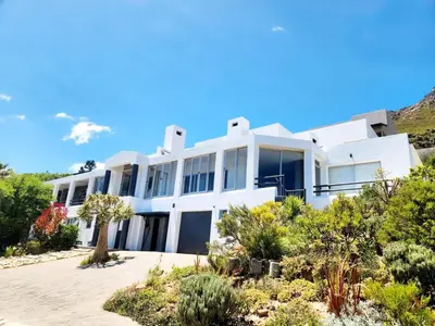 a white house with a lot of plants at Apartment in Gordon's Bay in Gordonʼs Bay