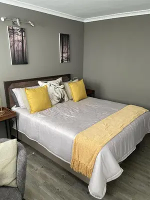 a bedroom with a large bed with yellow pillows at Apartment in Gordon's Bay in Gordonʼs Bay