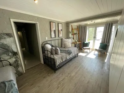 a bedroom with a bed and a chair in a room at Apartment in Gordon's Bay in Gordonʼs Bay