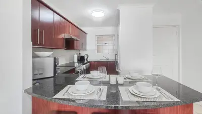 a kitchen with a table with plates and wine glasses at Homely 3 Bedroom apartment in Villa Italia Century City in Cape Town