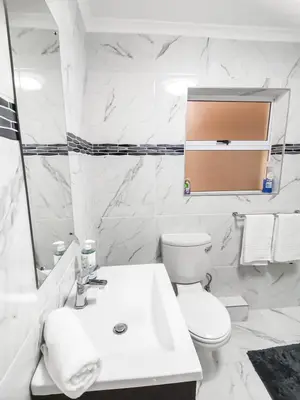 a white bathroom with a toilet and a sink at Homely 3 Bedroom apartment in Villa Italia Century City in Cape Town