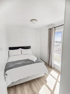 a white bedroom with a bed and a window at Homely 3 Bedroom apartment in Villa Italia Century City in Cape Town