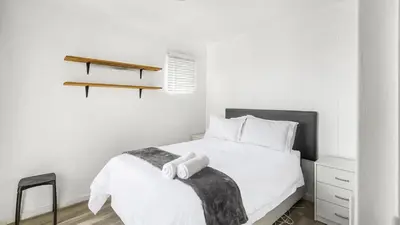 a bedroom with a white bed with a black and white blanket at Homely 3 Bedroom apartment in Villa Italia Century City in Cape Town