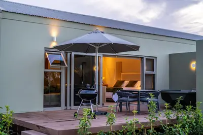 a patio with an umbrella and a table and chairs at LEO Sky Farm Cottages in Simondium