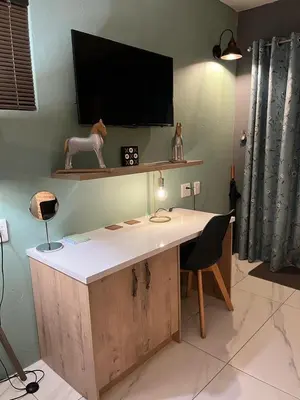 a office with a desk with a tv on the wall at Southern Comfort Guest House in Bellville