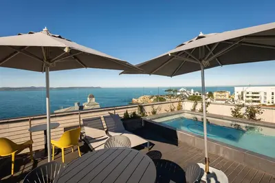 a balcony with a swimming pool and chairs and umbrellas at Mountain-View Studio - Hermanus Waterfront Apartments in Hermanus