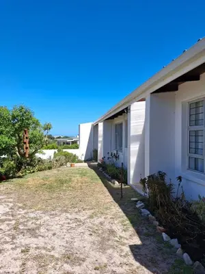 a white house with a yard next to it at Alibi at the Sea in Bettyʼs Bay