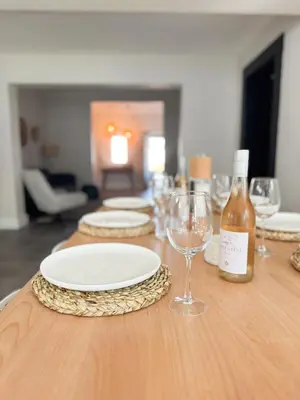 a wooden table with plates and wine glasses on it at Stunning Home in Hermanus Town Centre in Hermanus