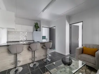a kitchen with a counter and stools in a living room at 4 Essex Street Apartment in Cape Town