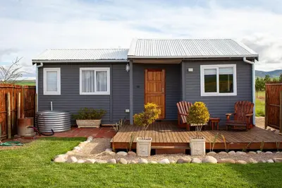 a tiny house with a deck and two chairs at Kleinhuisie in Hermon