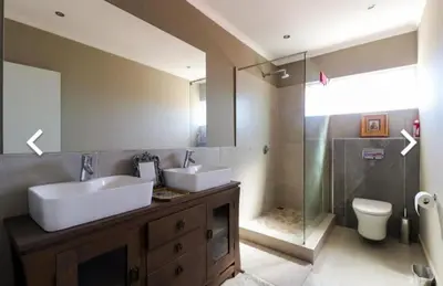 a bathroom with two sinks and a glass shower at Close to the sea and sea path in Hermanus