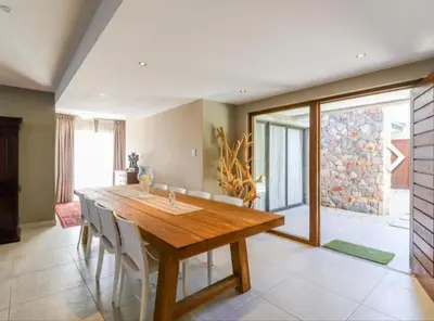 a dining room with a wooden table and chairs at Close to the sea and sea path in Hermanus