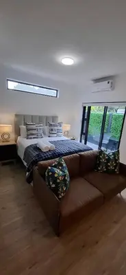 a bedroom with a large bed and a couch at Blouberg Luxury Studio Apartment in Cape Town