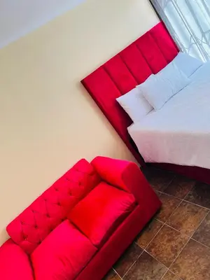 a bedroom with a red bed and a red couch at AFRICAN HAVEN GUEST HOUSE BnB GOODWOOD in Cape Town