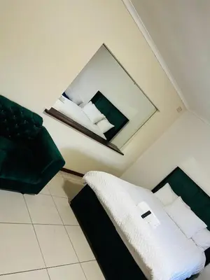 a bedroom with a bed with a mirror and a chair at AFRICAN HAVEN GUEST HOUSE BnB GOODWOOD in Cape Town