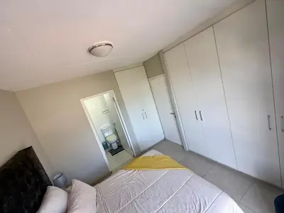 a small bedroom with a bed and white cabinets at Elegant 2 bedroom apartment with Mountain Views in Cape Town