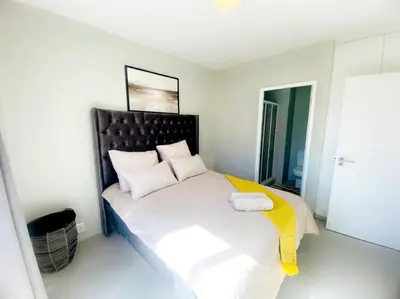 a bedroom with a large bed with a black headboard at Elegant 2 bedroom apartment with Mountain Views in Cape Town