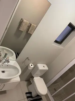 a white bathroom with a toilet and a sink at Elegant 2 bedroom apartment with Mountain Views in Cape Town
