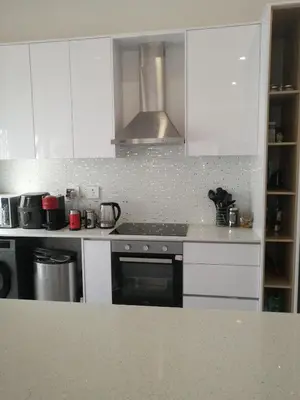 a kitchen with white cabinets and a stove top oven at Sandown Sun in Cape Town