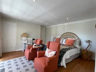 a bedroom with a bed and two chairs at Wholeness Accommodation in Hermanus