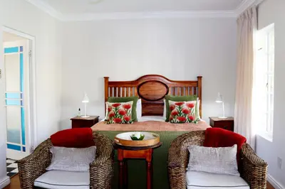 a bedroom with a bed with two chairs and a table at Wholeness Accommodation in Hermanus