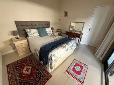 a bedroom with a bed and a desk and a mirror at Strand cosy 2 bedroom house in Strand