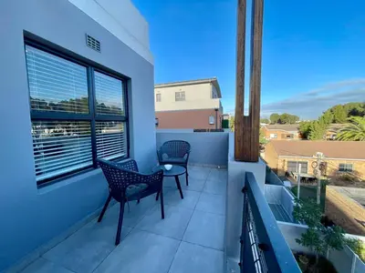 a balcony with two chairs and a window at 18 On 40 North in Cape Town