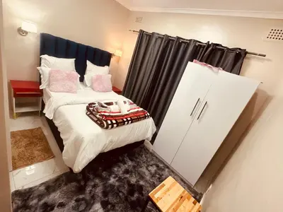 a small bedroom with a bed and a refrigerator at Forest Home Accommodation in De Grendel