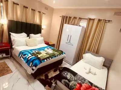 a small bedroom with a bed and a refrigerator at Forest Home Accommodation in De Grendel