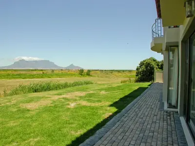 a house with a brick walkway next to a field of grass at Castellon Boutique Hotel in Table View
