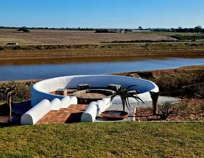 a blue and white boat on a field with a river at Hermanus - Escape Wines - House on Wine & Protea farm in Lake Marina