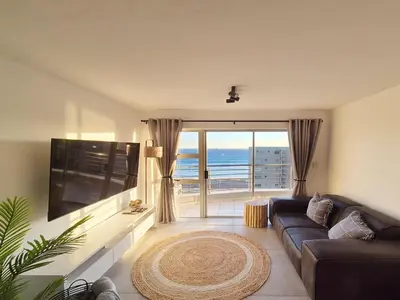a living room with a couch and a view of the ocean at Luxurious Ocean View Beachfront Apartment in Cape Town