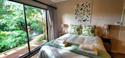 a bedroom with a bed and a large window at Tuinvrede Guesthouse in Welgemoed