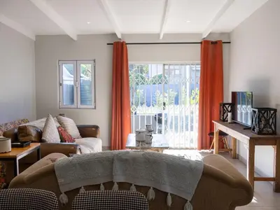 a living room with orange curtains and a couch at The Grey Hound in Strand